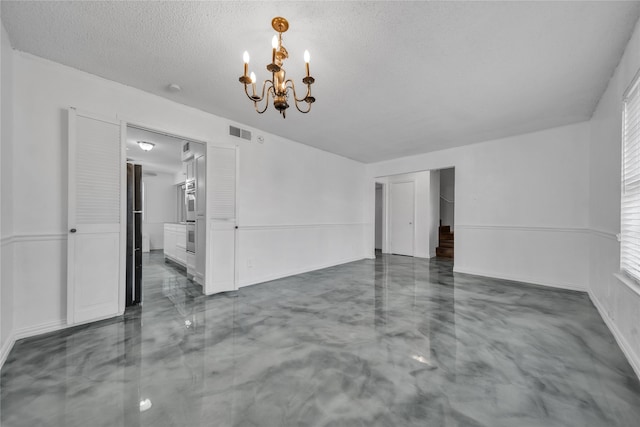 empty room featuring a textured ceiling and a notable chandelier