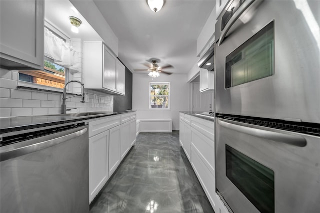 kitchen with sink, white cabinets, stainless steel appliances, backsplash, and ceiling fan