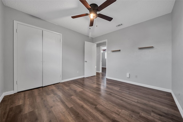 unfurnished bedroom with dark hardwood / wood-style flooring, a closet, ceiling fan, and a textured ceiling