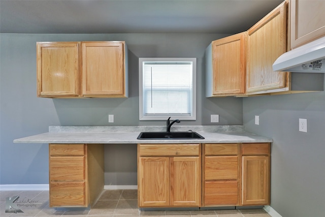 kitchen with light brown cabinetry, light tile patterned floors, sink, and range hood