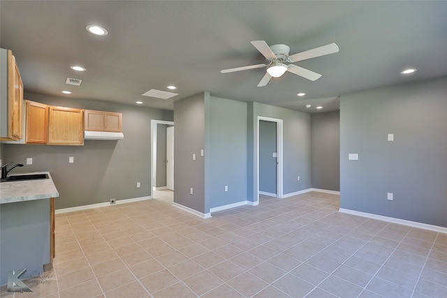 kitchen with light tile patterned floors, light brown cabinetry, ceiling fan, and sink