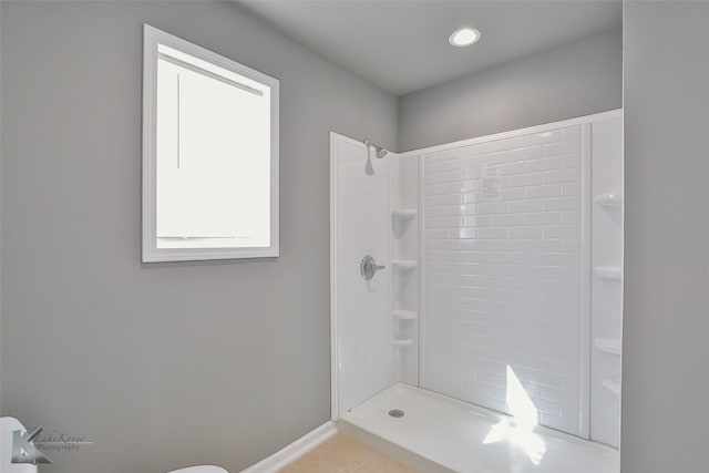 bathroom with toilet, tile patterned floors, and tiled shower