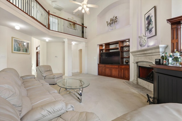 living room featuring decorative columns, a towering ceiling, ceiling fan, and light colored carpet