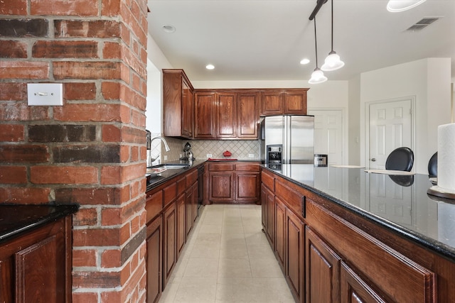 kitchen with stainless steel refrigerator with ice dispenser, decorative backsplash, light tile patterned floors, dark stone counters, and sink