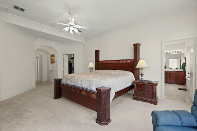 bedroom with ceiling fan, a walk in closet, a closet, light carpet, and crown molding