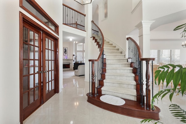 foyer featuring a notable chandelier, a high ceiling, decorative columns, and french doors