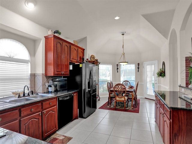 kitchen featuring pendant lighting, lofted ceiling, light tile patterned floors, sink, and black dishwasher