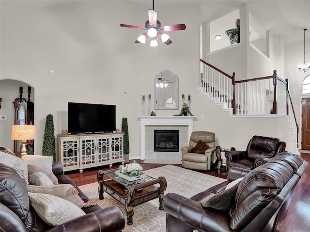 living room featuring ceiling fan, hardwood / wood-style flooring, a fireplace, and a towering ceiling