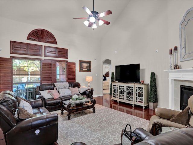 living room featuring a tile fireplace, dark hardwood / wood-style flooring, ceiling fan, and high vaulted ceiling