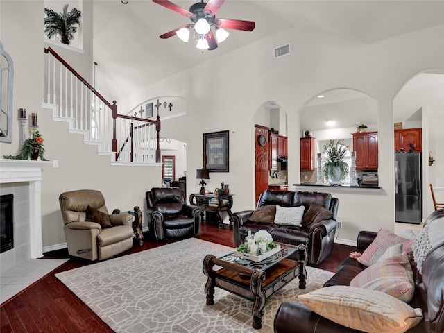 living room featuring light hardwood / wood-style floors, a fireplace, ceiling fan, and high vaulted ceiling