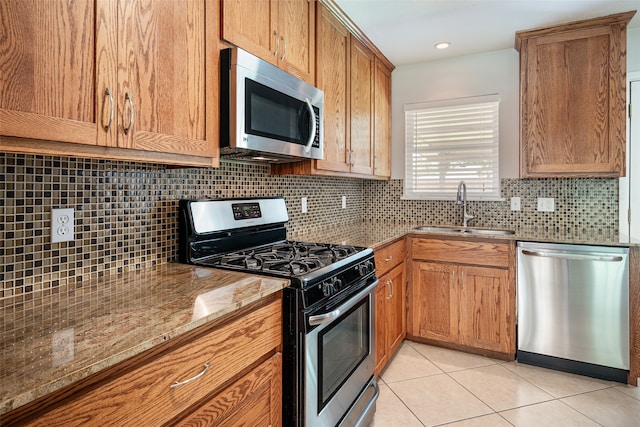 kitchen with tasteful backsplash, appliances with stainless steel finishes, sink, and light tile patterned floors