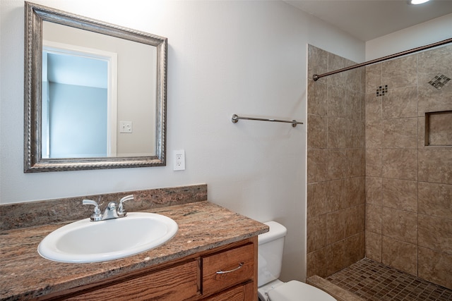 bathroom with vanity, toilet, and a tile shower