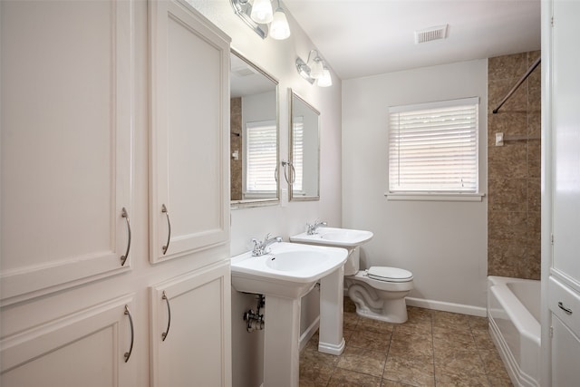 bathroom with double sink, tiled shower / bath, tile patterned floors, and toilet