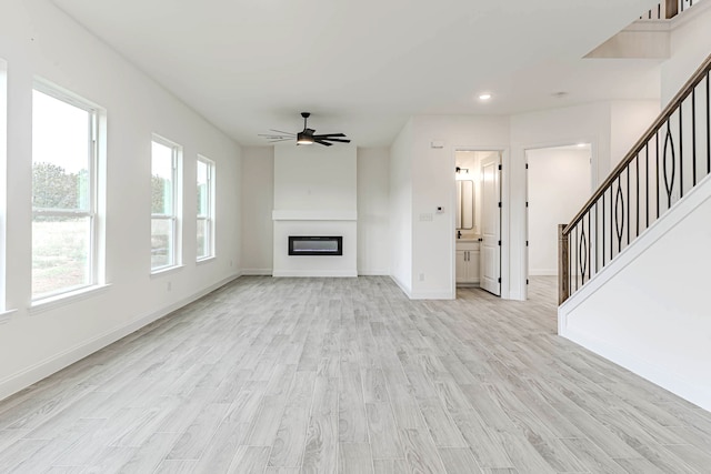 unfurnished living room featuring ceiling fan and light wood-type flooring