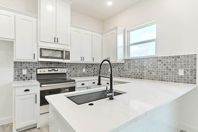 kitchen featuring light wood-type flooring, tasteful backsplash, sink, white cabinetry, and appliances with stainless steel finishes