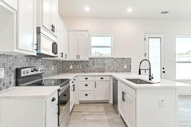 kitchen with light wood-type flooring, white cabinetry, appliances with stainless steel finishes, and plenty of natural light