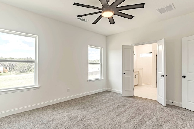 unfurnished bedroom with multiple windows, light colored carpet, and ceiling fan