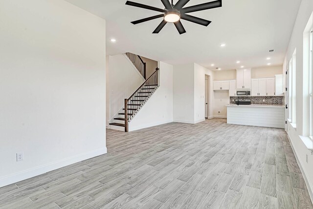 unfurnished living room featuring ceiling fan and light hardwood / wood-style floors