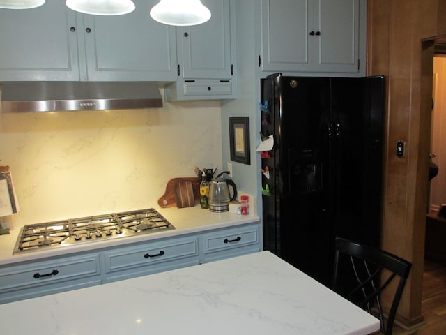 401 Craig St, Hillsboro, TX 76645 - kitchen featuring wall chimney exhaust hood, stainless steel gas cooktop, black refrigerator with ice dispenser, light stone countertops, and hanging light fixtures