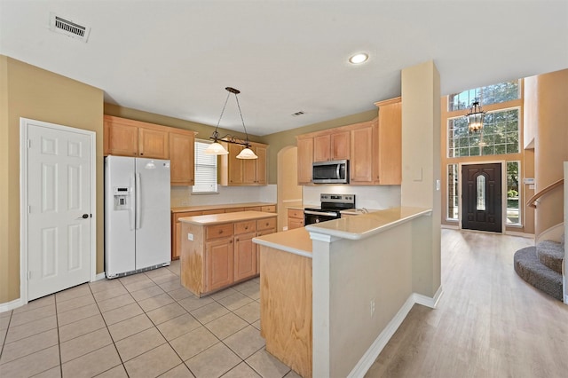 kitchen with kitchen peninsula, light brown cabinets, light tile patterned floors, pendant lighting, and stainless steel appliances