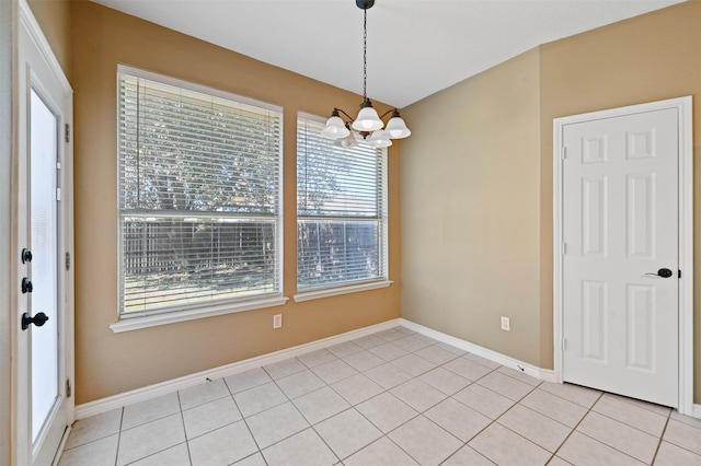 spare room with a notable chandelier and light tile patterned floors