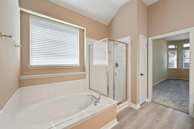 bathroom featuring vaulted ceiling, hardwood / wood-style flooring, a healthy amount of sunlight, and separate shower and tub