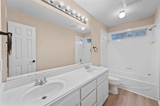 full bathroom with vanity, hardwood / wood-style flooring, tiled shower / bath combo, and toilet