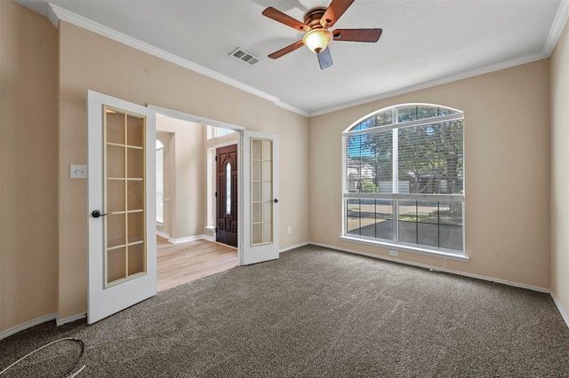 spare room with french doors, carpet floors, crown molding, and ceiling fan