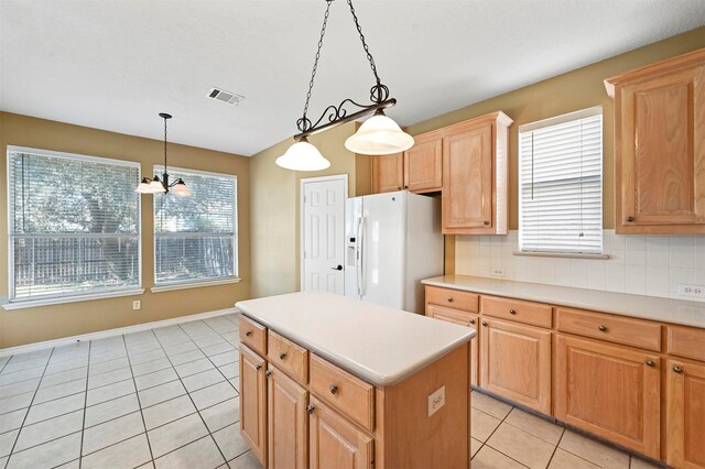 kitchen featuring a chandelier, a center island, white refrigerator with ice dispenser, hanging light fixtures, and decorative backsplash