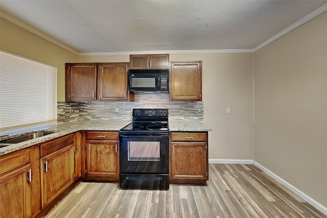 kitchen featuring ornamental molding, black appliances, light hardwood / wood-style floors, and a textured ceiling