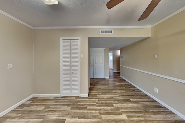 empty room with a textured ceiling, light hardwood / wood-style floors, ceiling fan, and crown molding