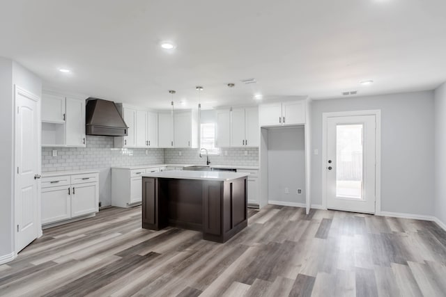 kitchen featuring custom range hood, white cabinetry, a center island, and plenty of natural light