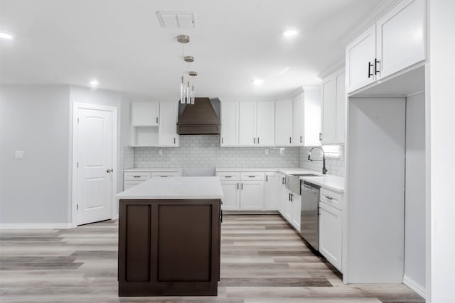 kitchen featuring white cabinets, sink, a kitchen island, custom range hood, and light wood-type flooring