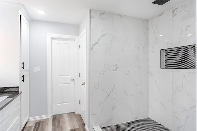 bathroom featuring wood-type flooring, vanity, and tiled shower