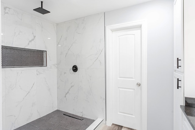 bathroom featuring wood-type flooring, vanity, and a tile shower