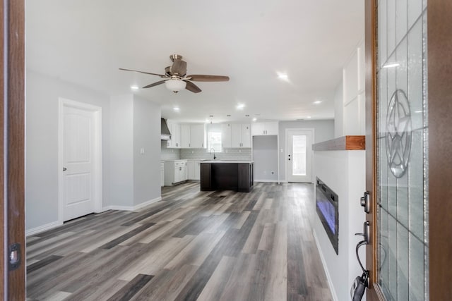 unfurnished living room featuring dark wood-type flooring, ceiling fan, and sink