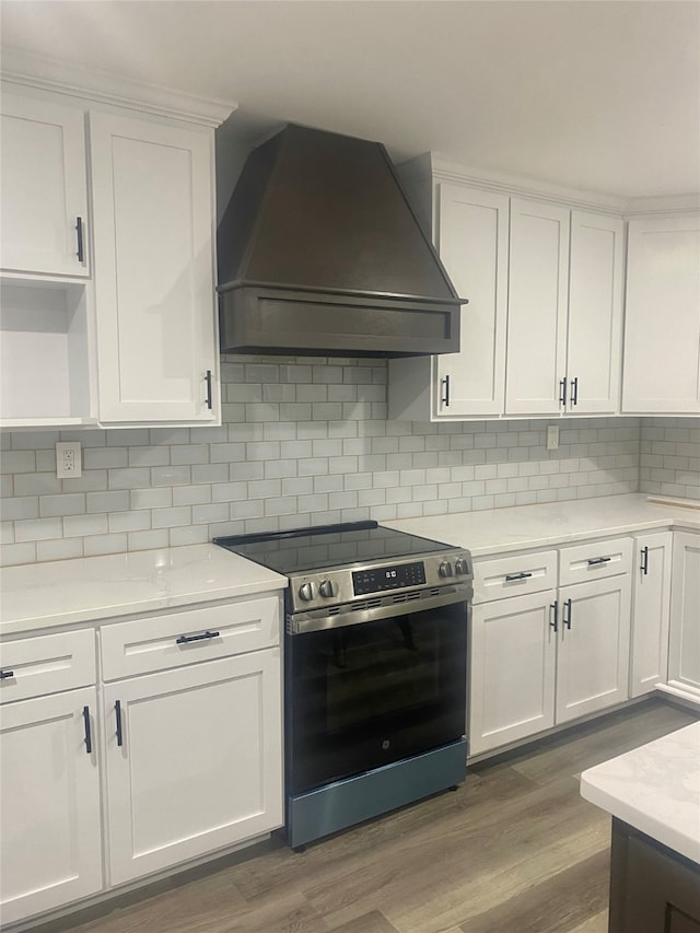 kitchen with stainless steel stove, white cabinetry, dark hardwood / wood-style floors, and custom exhaust hood