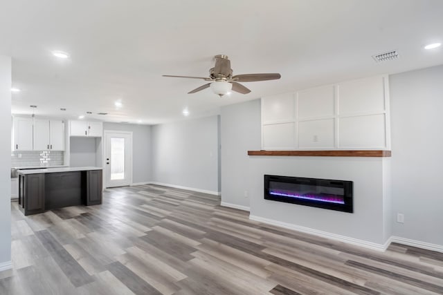 unfurnished living room with light hardwood / wood-style floors and ceiling fan