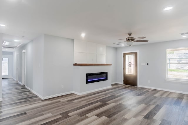 unfurnished living room with light hardwood / wood-style flooring, a large fireplace, and ceiling fan