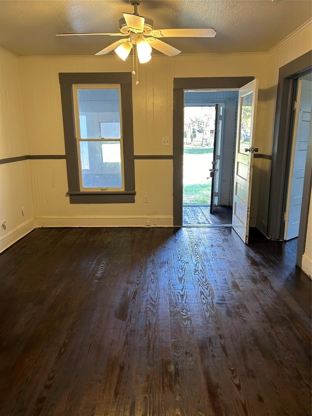 empty room with ceiling fan, dark wood-type flooring, and a textured ceiling