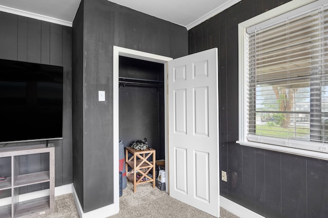 carpeted bedroom featuring crown molding, wooden walls, and a closet