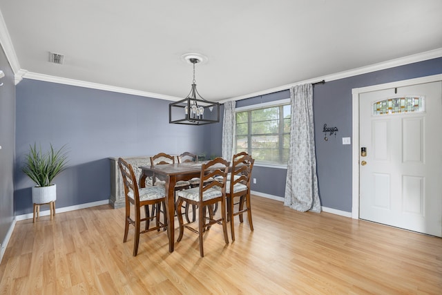 dining area with ornamental molding, a notable chandelier, and light hardwood / wood-style floors