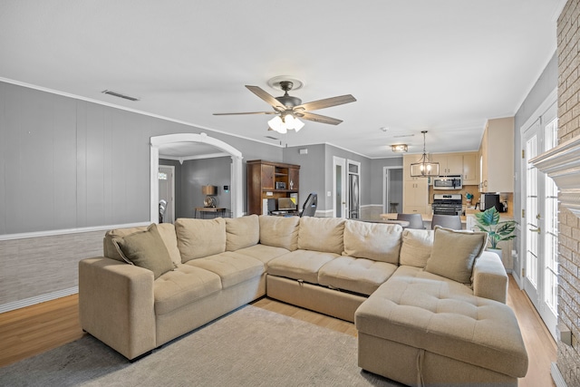 living room with ceiling fan with notable chandelier, light hardwood / wood-style floors, crown molding, and french doors