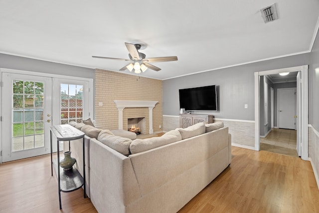 living room featuring ceiling fan, a fireplace, french doors, and light hardwood / wood-style floors