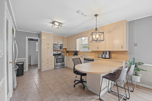 kitchen with appliances with stainless steel finishes, hanging light fixtures, a breakfast bar area, crown molding, and sink