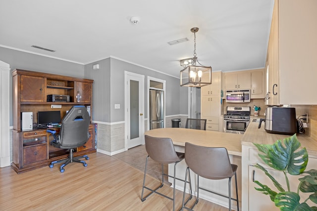 kitchen featuring hanging light fixtures, kitchen peninsula, light hardwood / wood-style flooring, appliances with stainless steel finishes, and a breakfast bar