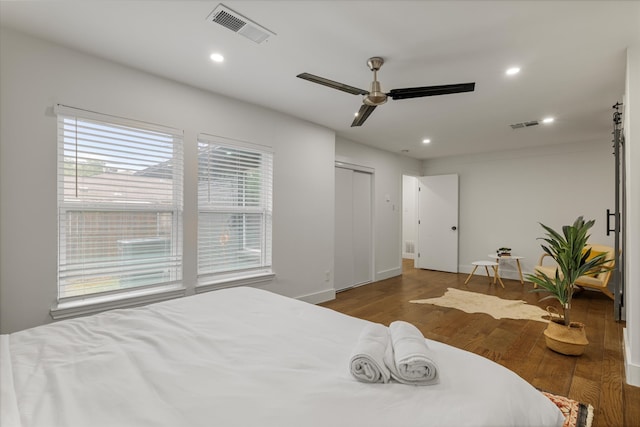 bedroom featuring ceiling fan, a closet, dark wood-type flooring, and multiple windows