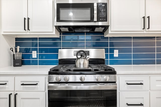 kitchen featuring decorative backsplash, white cabinets, and appliances with stainless steel finishes