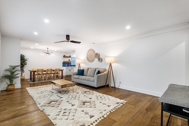 living room featuring crown molding, ceiling fan, and dark wood-type flooring