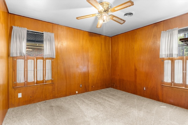 unfurnished room featuring carpet floors, wooden walls, and ceiling fan